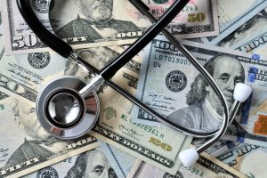 Stethoscope laying on money - Medical costs, doctor's bills, cost of insurance HSA FSA medical