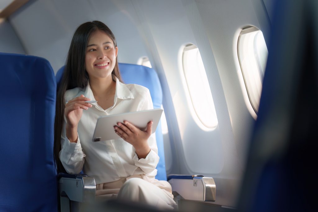 Beautiful Asian businesswoman working with digital tablet in aeroplane. working, travel, business